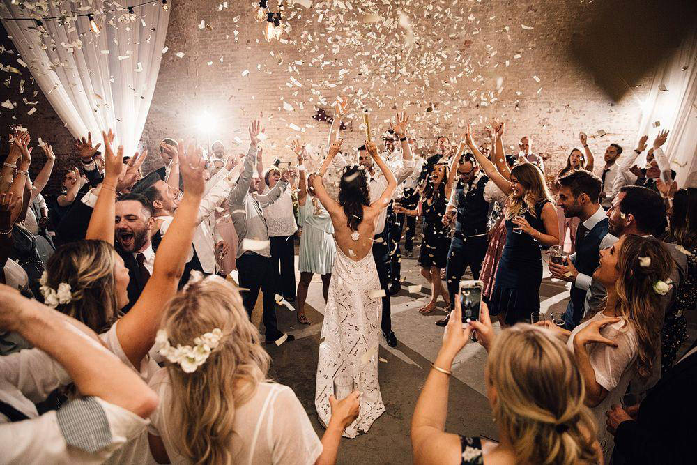 Bride and wedding guests with arms raised celebrating as confetti cannons fire across the dancefloor — confetti cannon hire in Worcestershire by Blue Diamond Entertainment