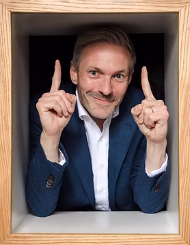 Wedding guest in navy blazer pointing upward with both hands inside a wooden box frame — Wedding Box Photo Booth portrait